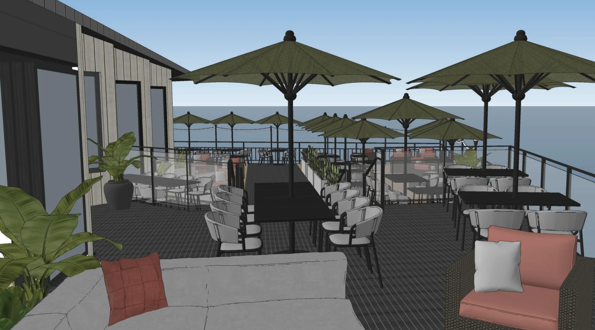 Outdoor patio with tables, chairs, and umbrellas; overlooks the ocean. Modern design with plants and cushioned seating. Black railing and string lights add to the ambiance.