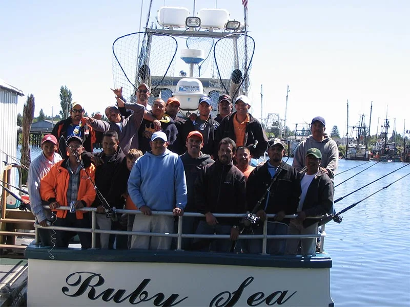 A group of people standing on the deck of a boat named 