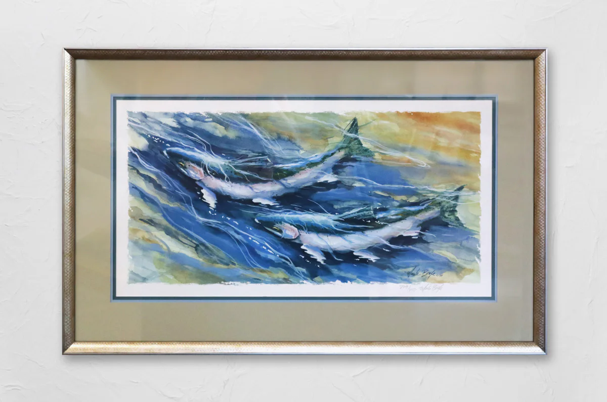 Framed watercolor painting depicting three fish swimming in dynamic blue and green waters, signed by the artist in the bottom right corner. The frame is metallic with a beige matte.