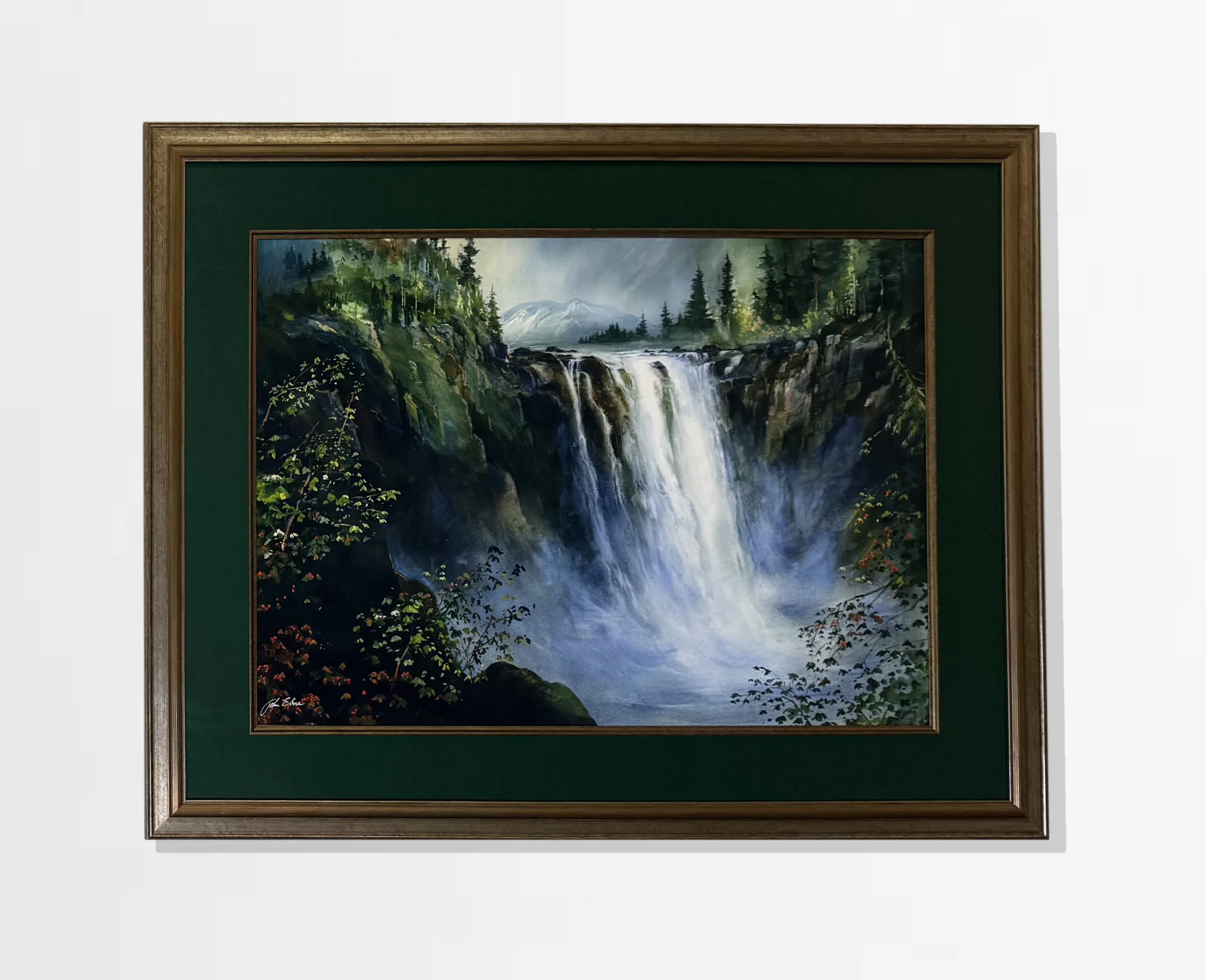 Framed painting of a waterfall cascading down rocky cliffs, surrounded by lush green trees and bushes. In the distance, snow-capped mountains under a cloudy sky.