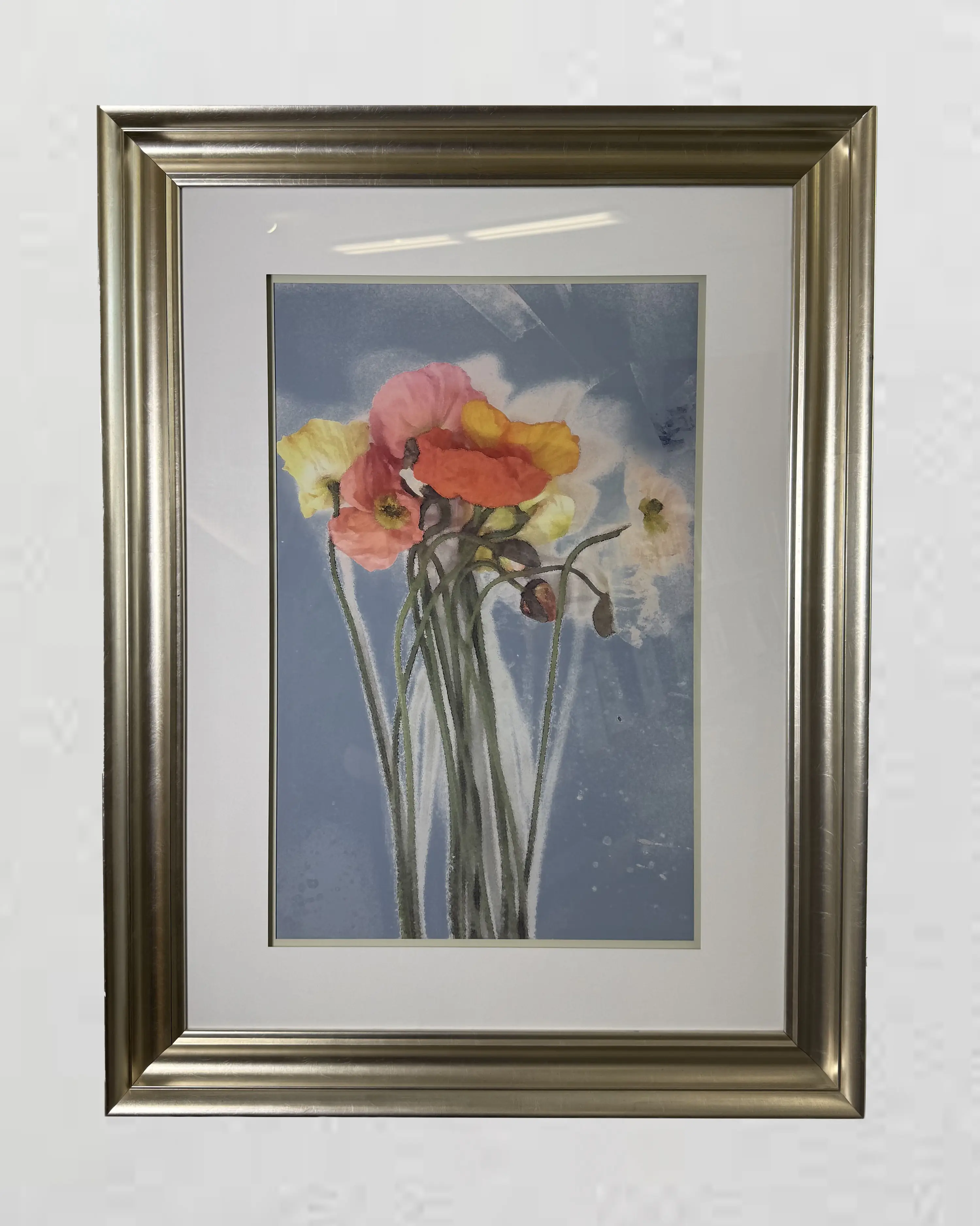 Painting of colorful flowers with long stems on a light blue background, framed in a metallic, silver-colored frame with a white mat.